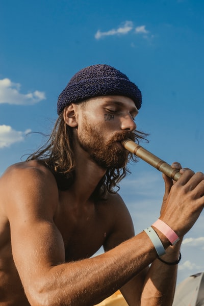 白天在蓝天下吹笛的赤裸上身男子